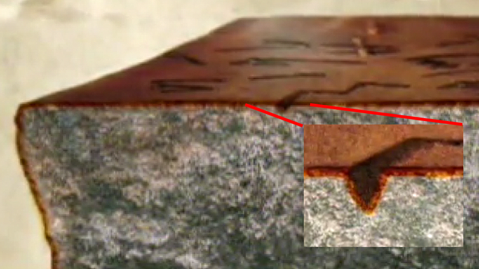 Roca con pátina y detalle de la letra