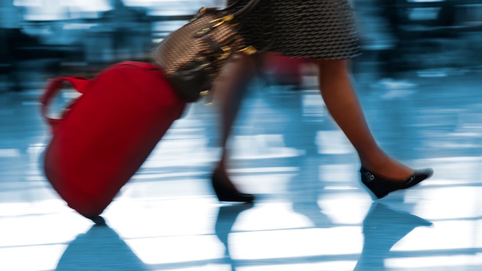 Una persona caminando por un aeropuerto con una maleta