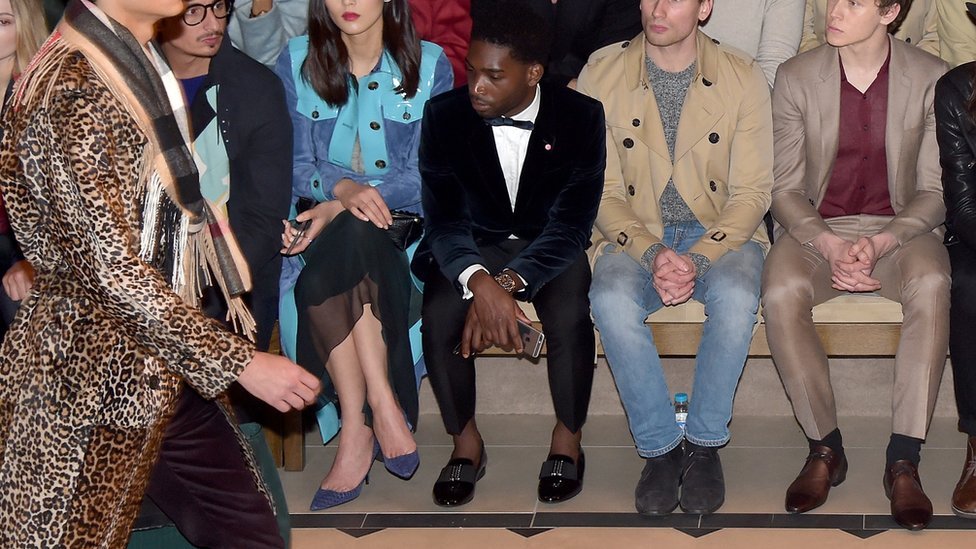 El cantante británico Tinie Tempah, mostrando sus tobillos en primera fila de un desfile de moda.