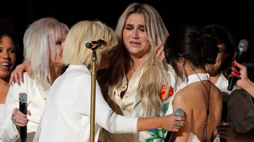 Kesha llora mientras sus otras compañeras en la presentación de los Grammy la abrazan.
