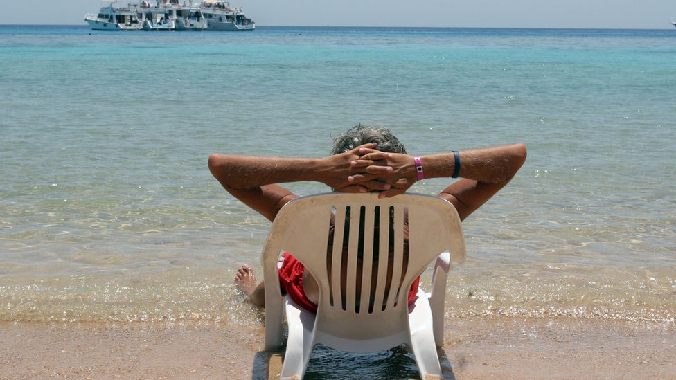 سائح ايطالي يجلس مستلقيا على أحد شواطئ منتجع شرم الشيخ المصري