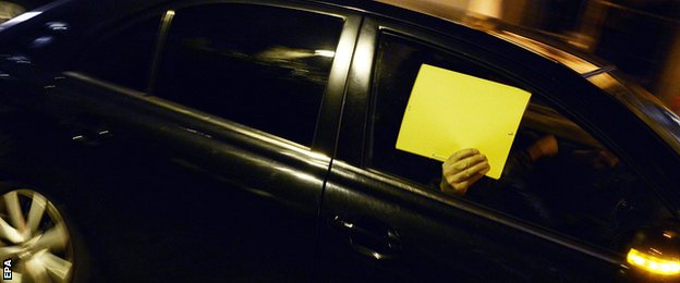 A man hides his face at the wheel of a car