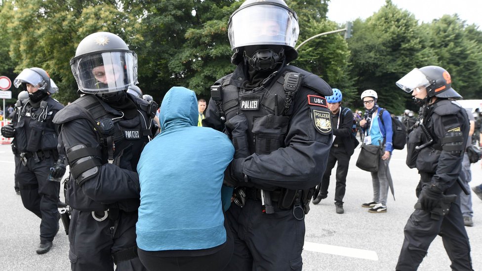 Hasil gambar untuk Seorang pengunjuk rasa diangkat secara paksa oleh polisi karena memblokir jalan menuju lokasi KTT G20