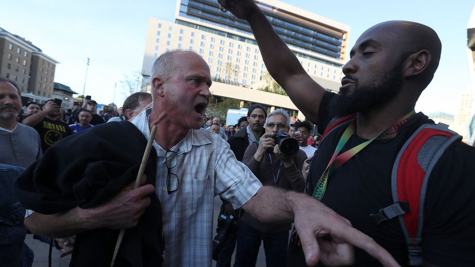 Un seguidor de baloncesto que intenta acceder al estadio discute con un manifestante del grupo 