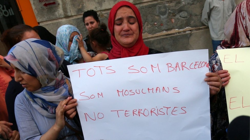 Mother of Said Aalla, Youssef Aalla and Mohamed Aalla holds a sign next to Hafida Oukabir (sister of suspect Moussa Oukabir) during a rally of the local Muslim community to denounce terrorism in front of Ripoll town hall. The sign reads: "We are Barcelona. We are Muslims, not terrorist". She is crying and is surrounded by other members of local community.