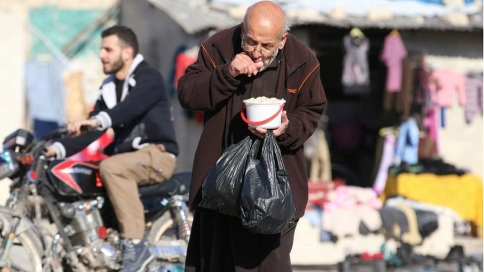 رجل مسن يحمل بعض الطعام الذي يوزع في المدينة