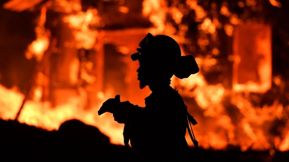 Silouette of firefighter with fire burning in background