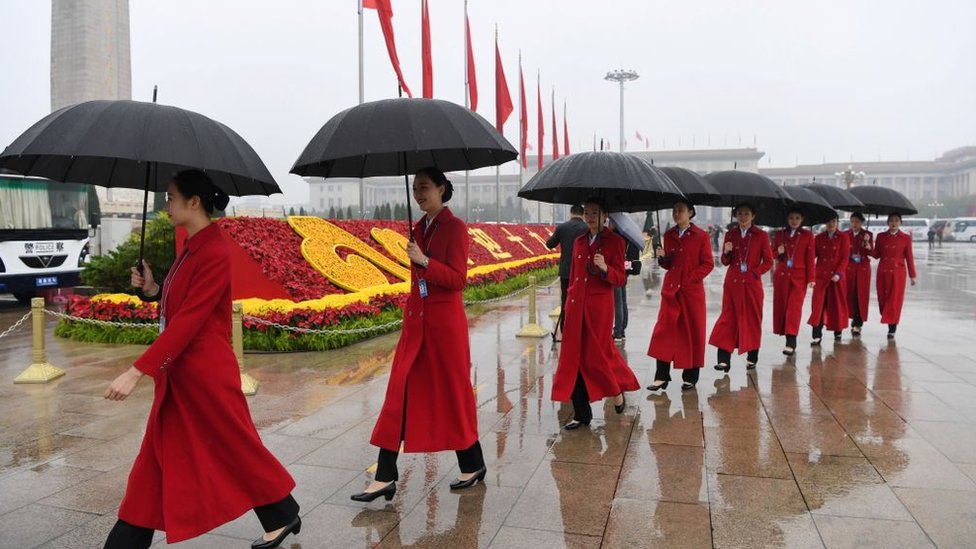 Xi describió varios planes para mejorar la calidad de vida de los habitantes de su país. Asistentes al congreso con paraguas en la plaza Tianamén.
