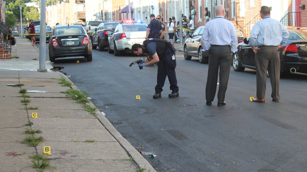 Detektif polisi Baltimore di lokasi pembunuhan di lingkungan Pigtown pada hari Sabtu