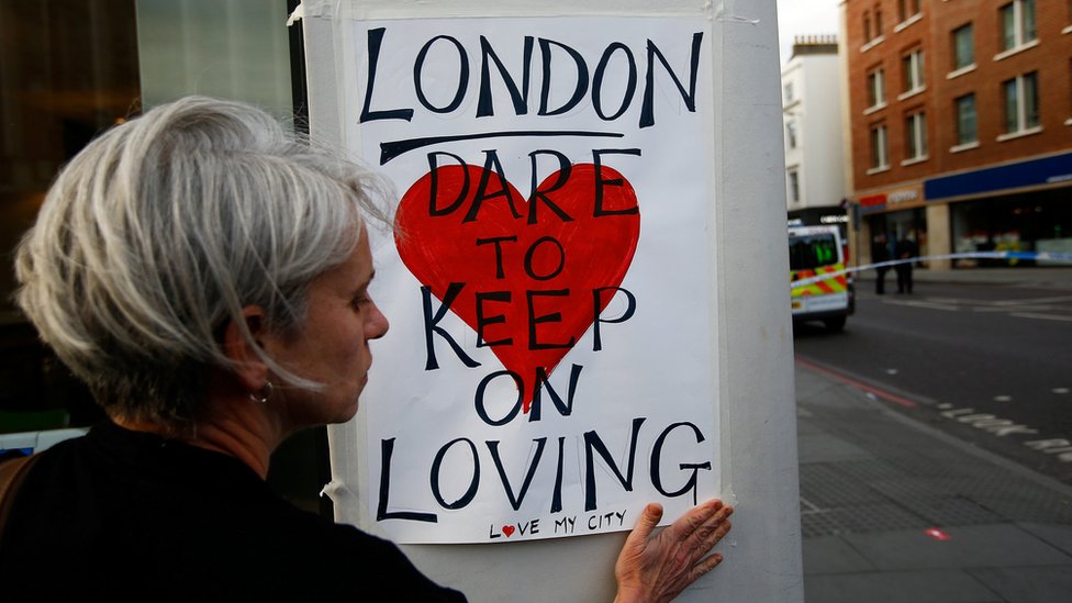 A woman sticks a sign up saying: