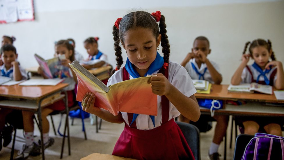 Niña cubana leyendo en clase