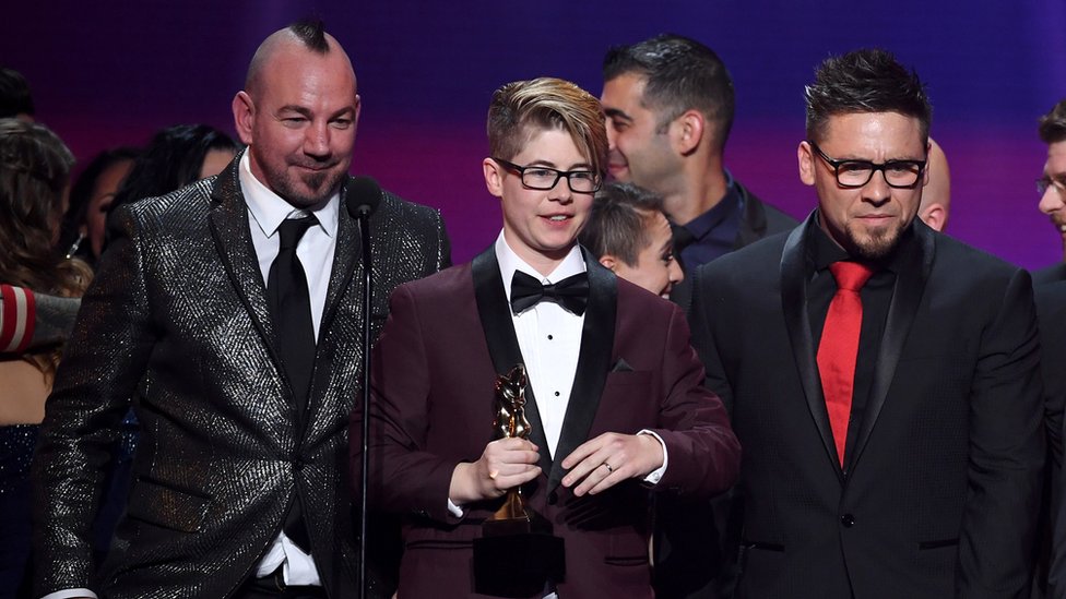 Bree Mills (centro) acepta el galardón a la Película del Año 2018, durante los Premios AVN, acompañada de su codirector Craven Moorehead (izq.) y el productor Billy Visual (der.)