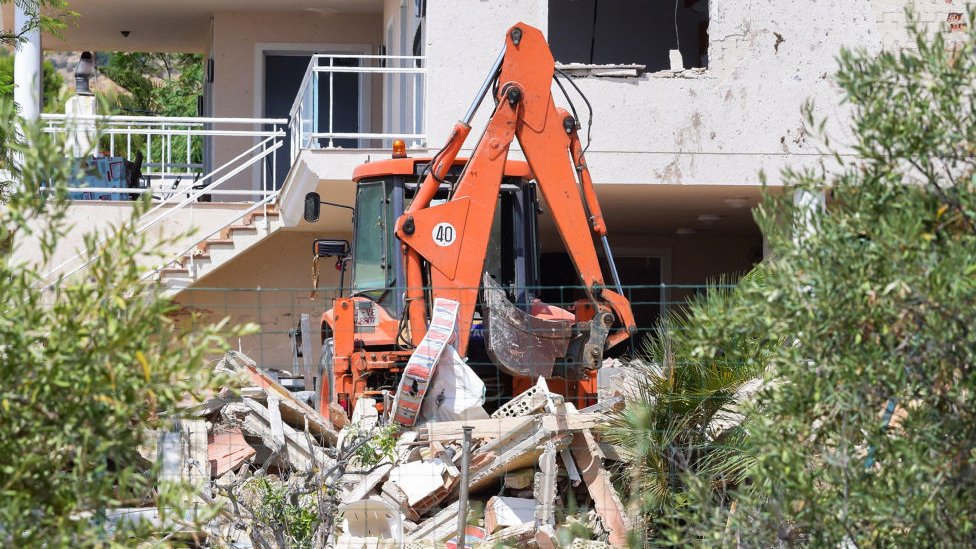 Una grúa trabaja en el desescombro de los restos de la casa de Alcanar