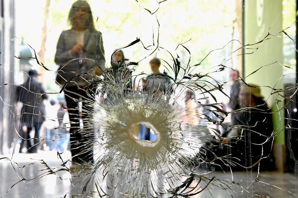 El incidente ocurrió alrededor de las 21:00 hora local (19:00 GMT) cerca del monumento Arco del Triunfo. People look at a bullet hole in a window near to the Marks and Spencer on the Champs Elysees in Paris following the shooting of a police officer, 21 April
