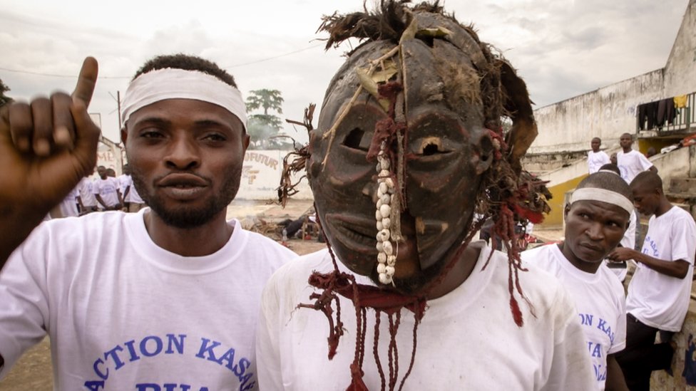 Dos jóvenes combatientes en la población de Kananga, uno de ellos con una máscara tradicional utilizada en ceremonias hechiceras.