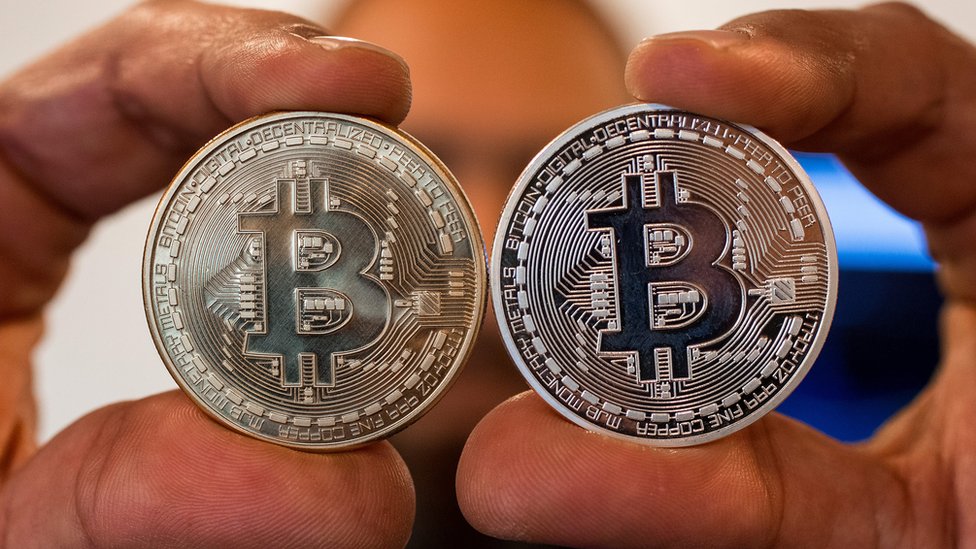 Dos manos sosteniendo un bitcoin cada una.