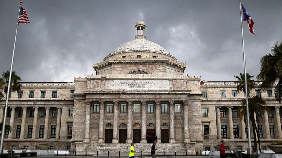 Capitolio de Puerto Rico con las banderas de Estados Unidos y Puerto Rico.