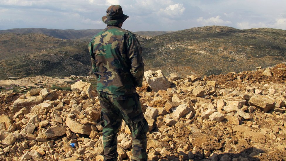 مقاتل من حزب الله ينظر إلى سوريا من وراء الحدود اللبنانية