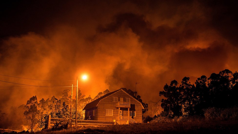 Según las autoridades gallegas, detrás de la mayoría de los incendios hay mano criminal. El fuego arde cerca de una casa en Nigrán, Galicia