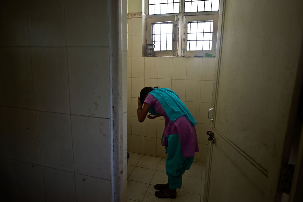 Una niña se lava en una estación de policía después de ser rescatada de unos traficantes.