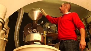 Peter Laszlo pours coffee beans into his roaster in his Budapest cafe, Lumen