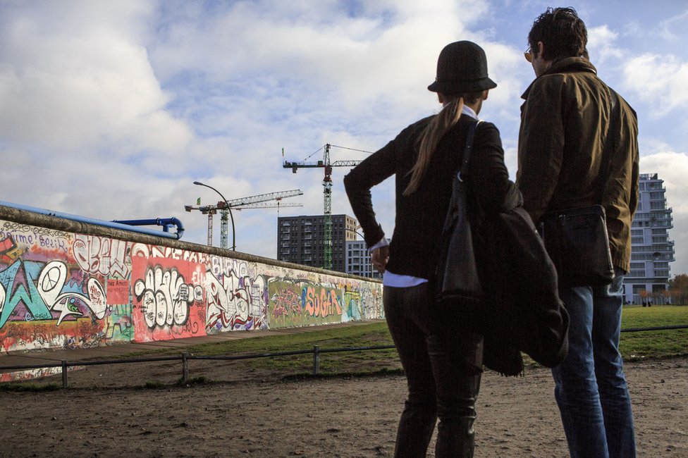 Una pareja mira una parte del muro de Berlín.