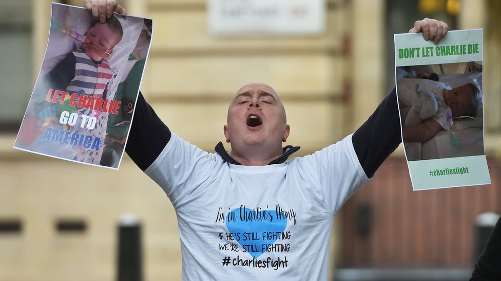 Hombre protestando frente a los tribunales con carteles que dicen: