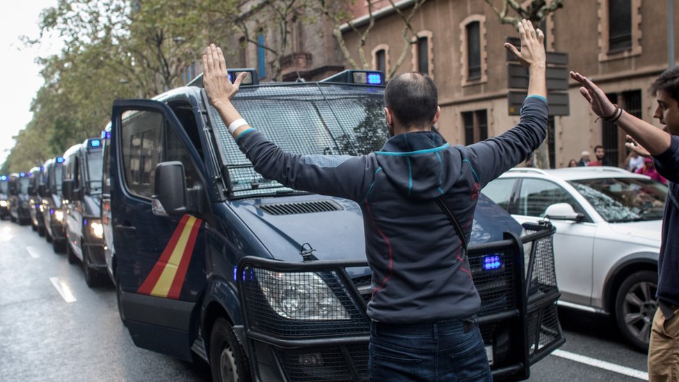 A man blocks a line of police truck as they try to control the area as people wait to cast their ballot in the referendum vote at Escola Industrial of Barcelona school polling station on October 1, 2017 in Barcelona, Spain.