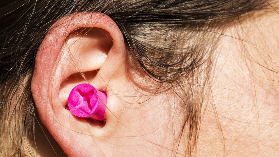 Oreja con un tapón fucsia.