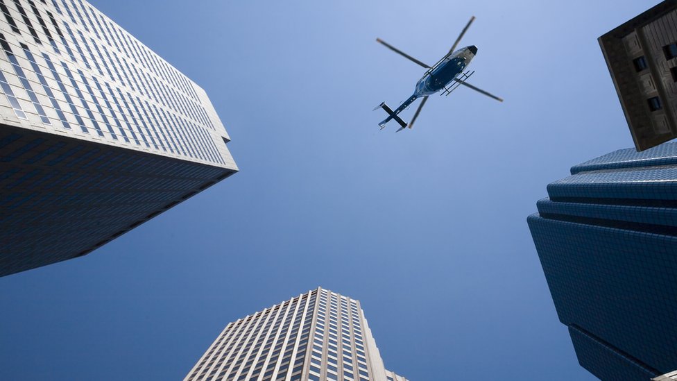 Vista al cielo de rascacielos y un helicóptero.