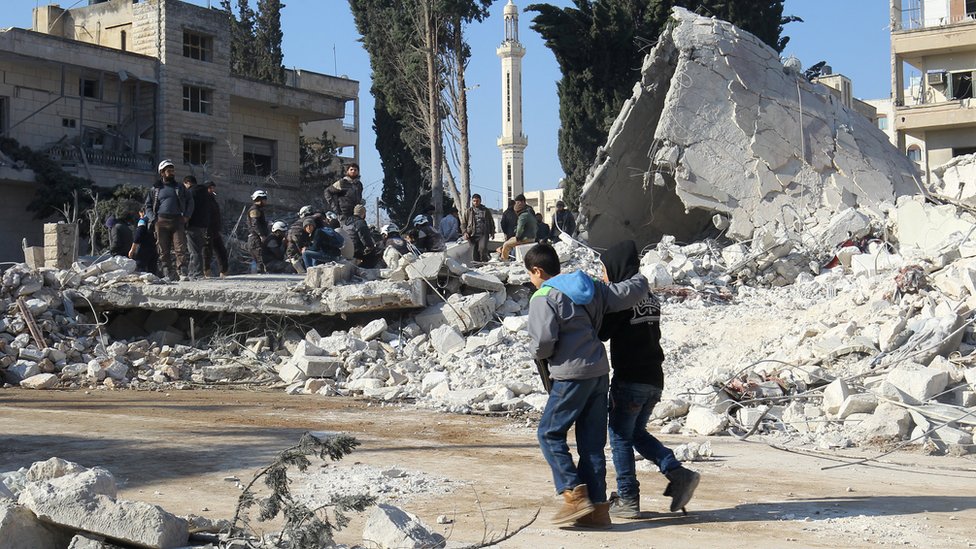 أطفال يسيرون جوار حطام أحد المنازل في سوريا