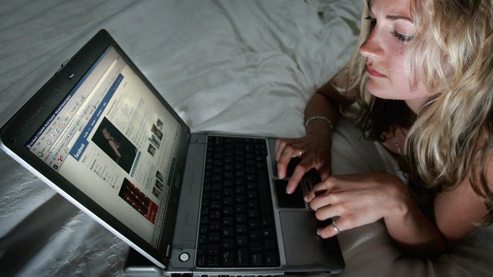 Mujer ve Facebook en su computadora portátil.