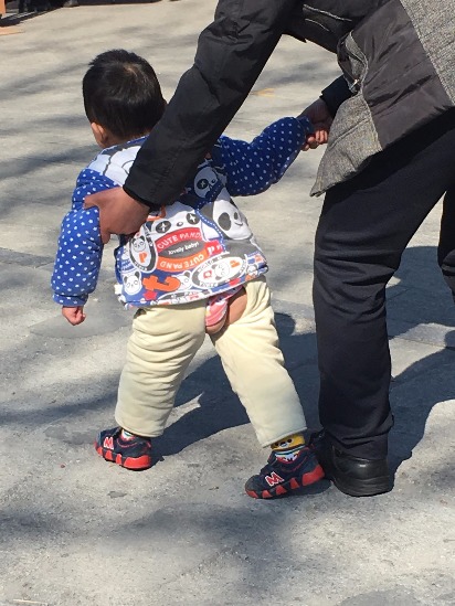 Niño en la calle usando un pantalón abierto.