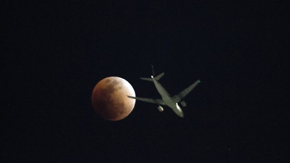 Un avión pasa enfrente de la superluna vista en Hong Kong.