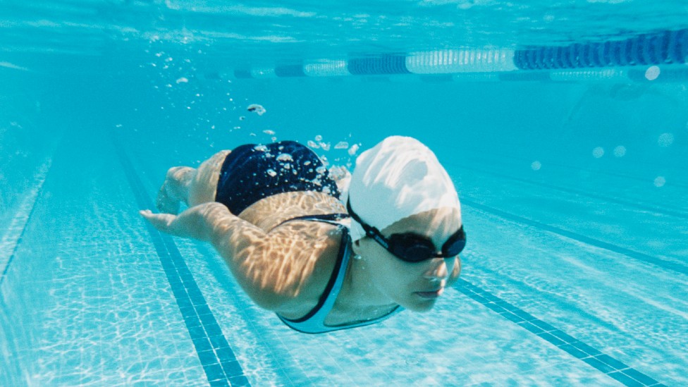 Hombre En Gafas Que Nada Debajo Del Agua En La Piscina Foto de