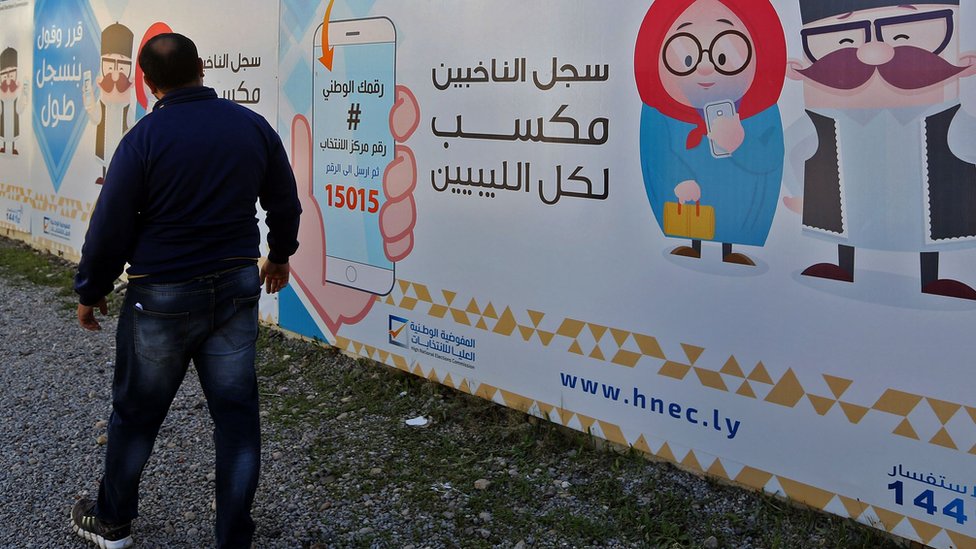 رجل يقف أمام ملصق دعائي للانتخابات