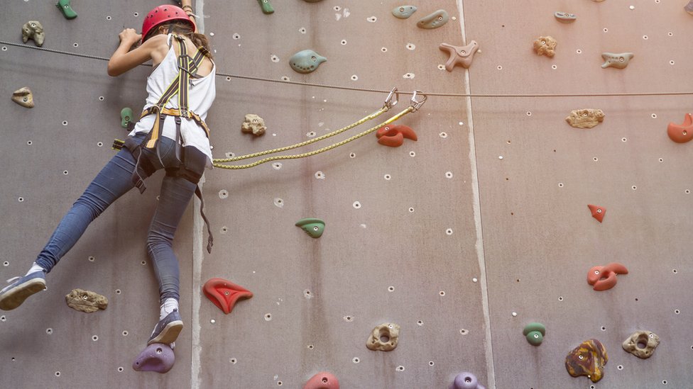 Una mujer escala en una pared