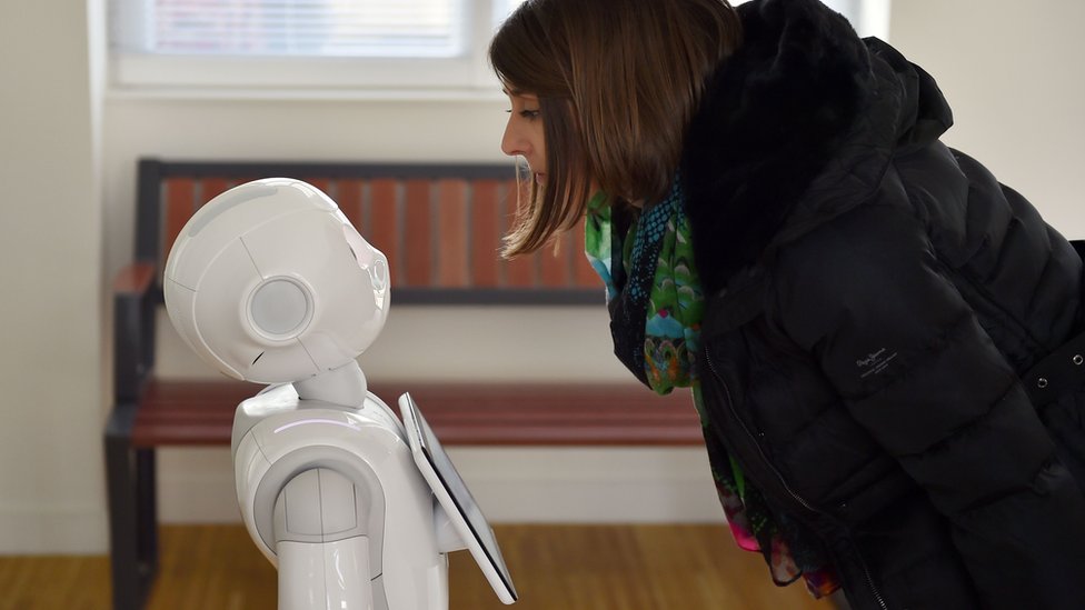 Woman looking down at Pepper the robot