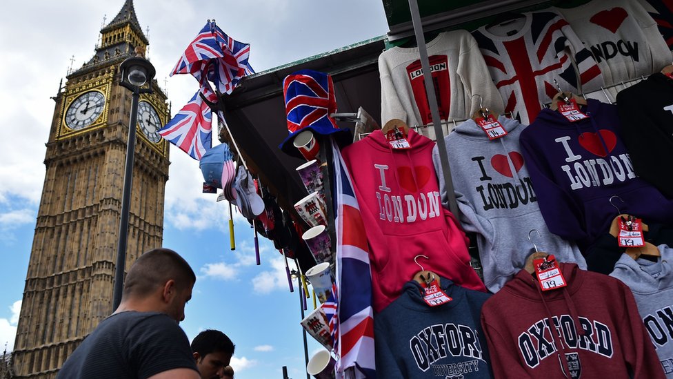 سواح يتفرجون على قمصان وتذكارات عليها صور لأبرز معالم لندن السياحية، وساعة بيغ بن في الخلفية.