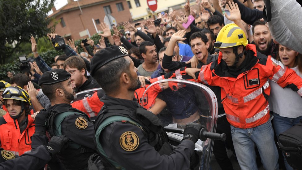 Firemen try to hold a group of people in front of Spanish Guardia Civil officers outside a polling station in San Julia de Ramis, on October 1, 2017, on the day of a referendum on independence for Catalonia banned by Madrid.