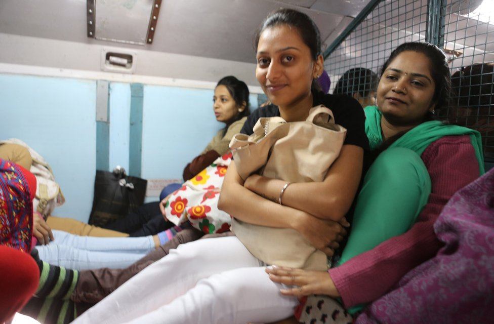 Pallavi (in green) sits with another woman on her lap
