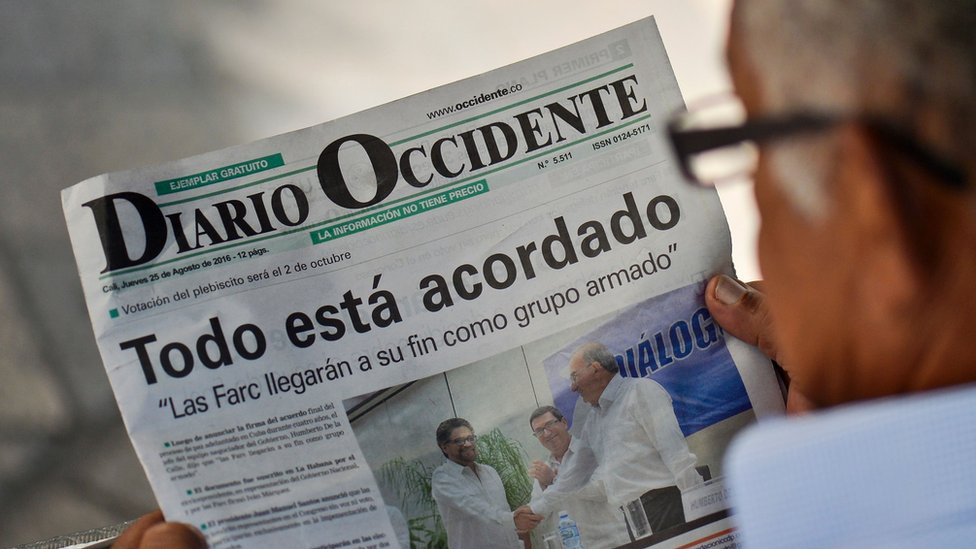 Un hombre lee un periódico anunciando el cierre de los acuerdos de paz en Colombia