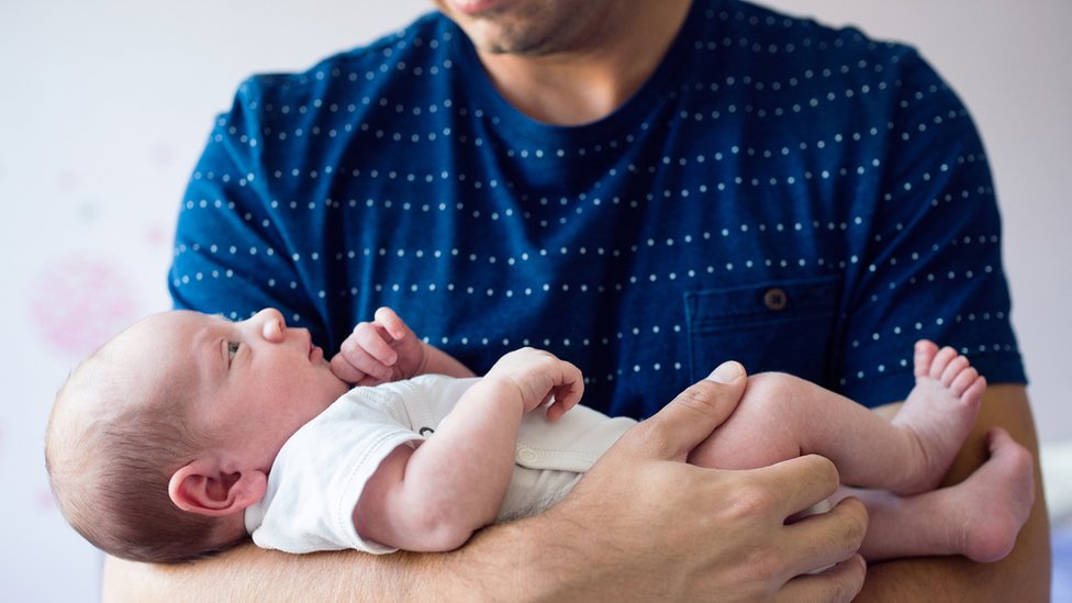 Un padre con un bebé en brazos.