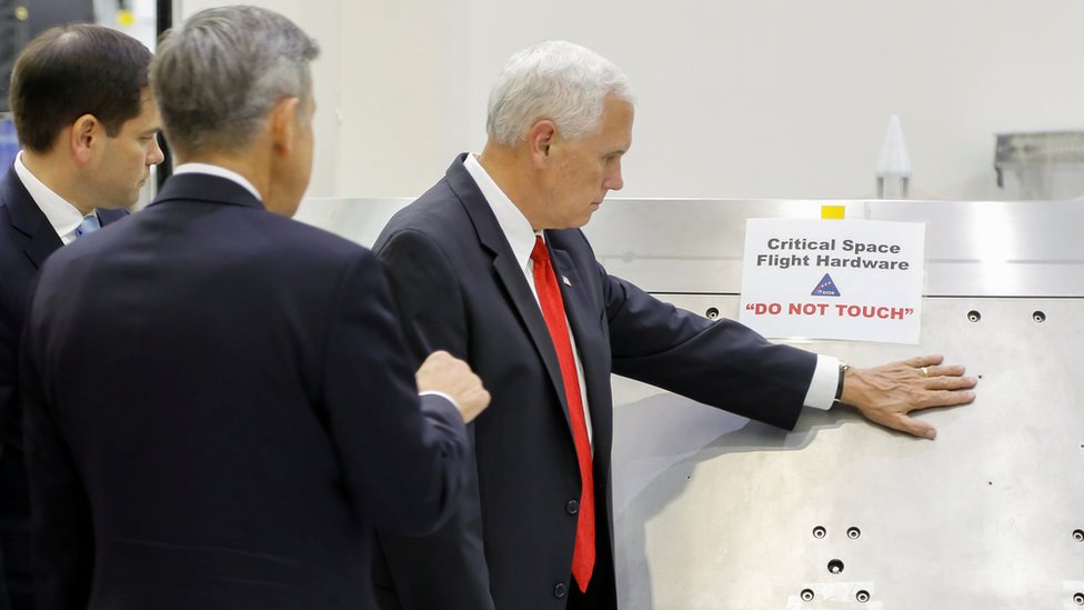 US Vice-President Mike Pence touches a piece of hardware with a warning label