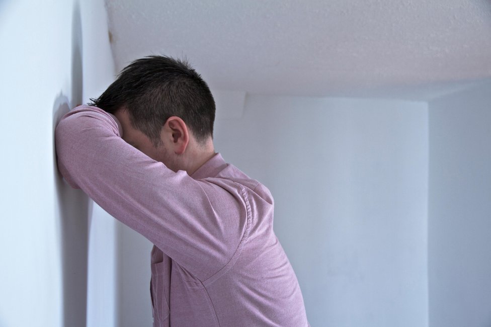 Hombre apoyado contra una pared