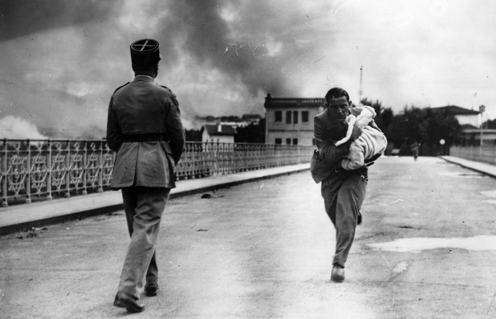 El periodista Raymond Walker, corre con un bebé en brazos sobre un puente entre Hendaya e Irún en plena guerra civil española.