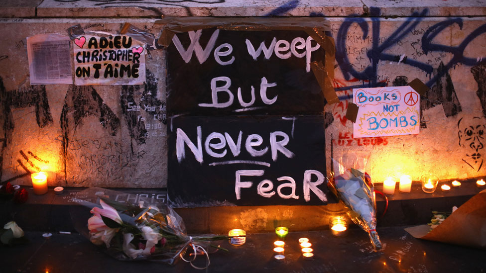A vigil in Paris with a sign reading "We weep but never fear"