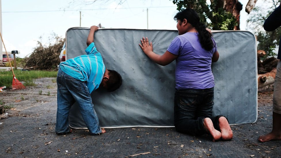 Dos niños limpian un colchón que se ensució por las inundaciones.