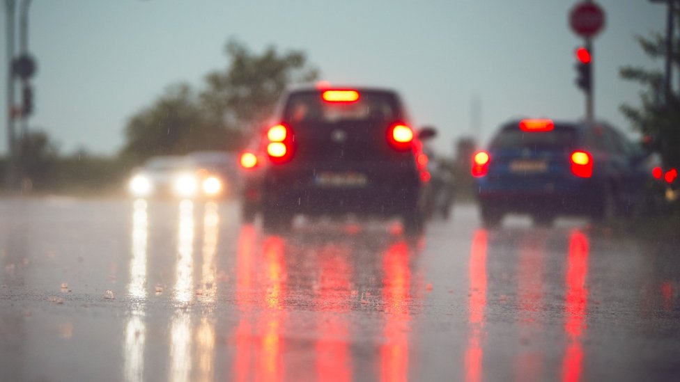 Autos vistos desde atrás, con las luces de frenos encendidas, en un día lluvioso