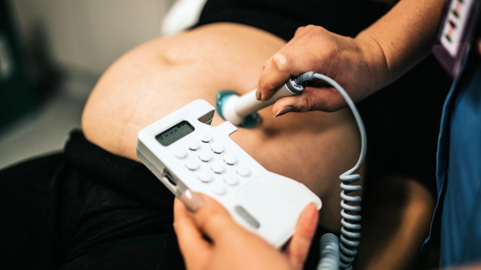 Mujer Embarazada Que Usa Dispositivo Doppler Fetal Para Escuchar El Latido  Del Corazón De Su Bebé En El Hospital Almacen De Video - Vídeo de escuchar,  instrumento: 262324743